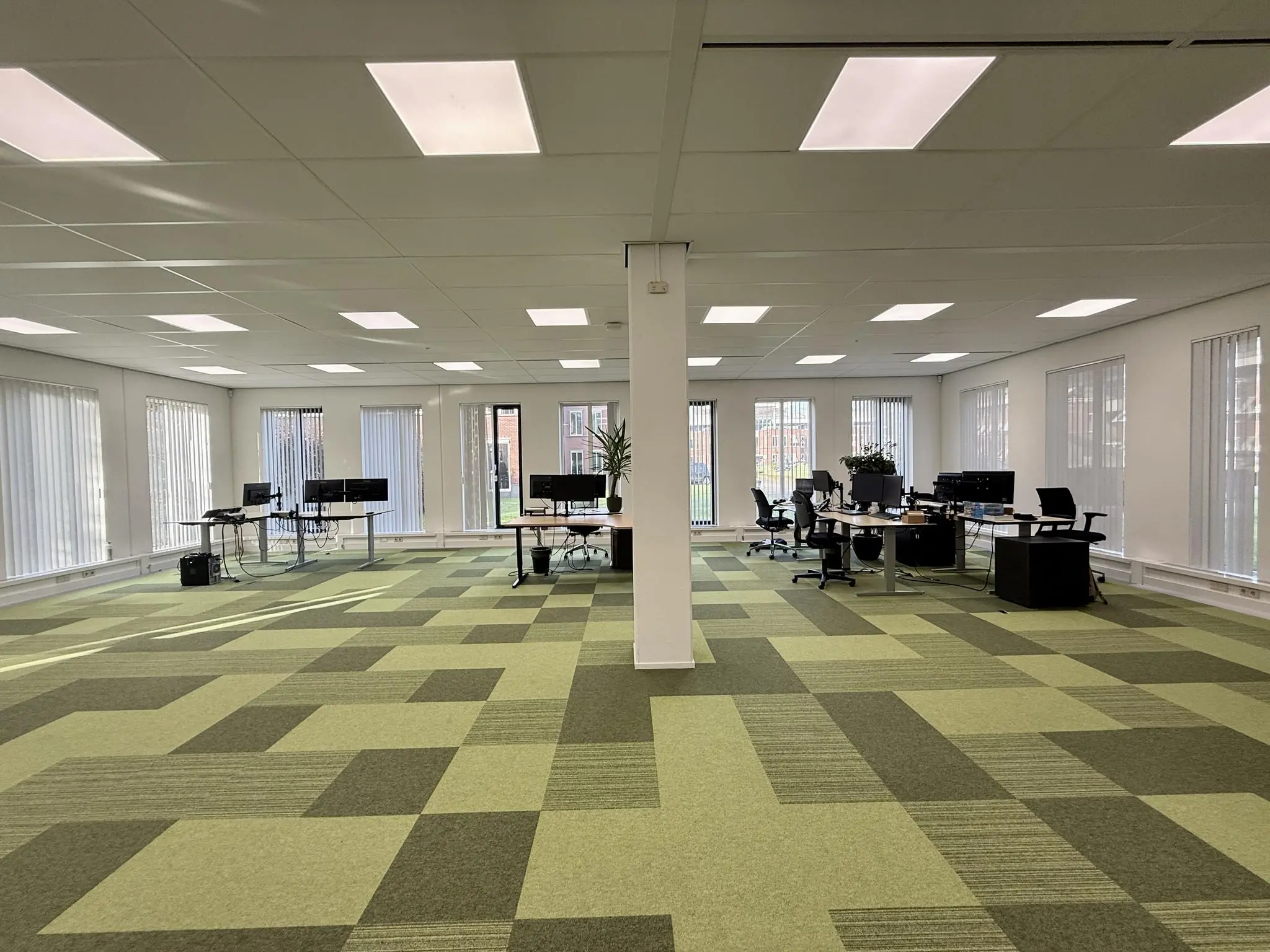 Ruim, modern kantoor met groene vloerbedekking en meerdere werkplekken aan de Arnhemse Bovenweg.